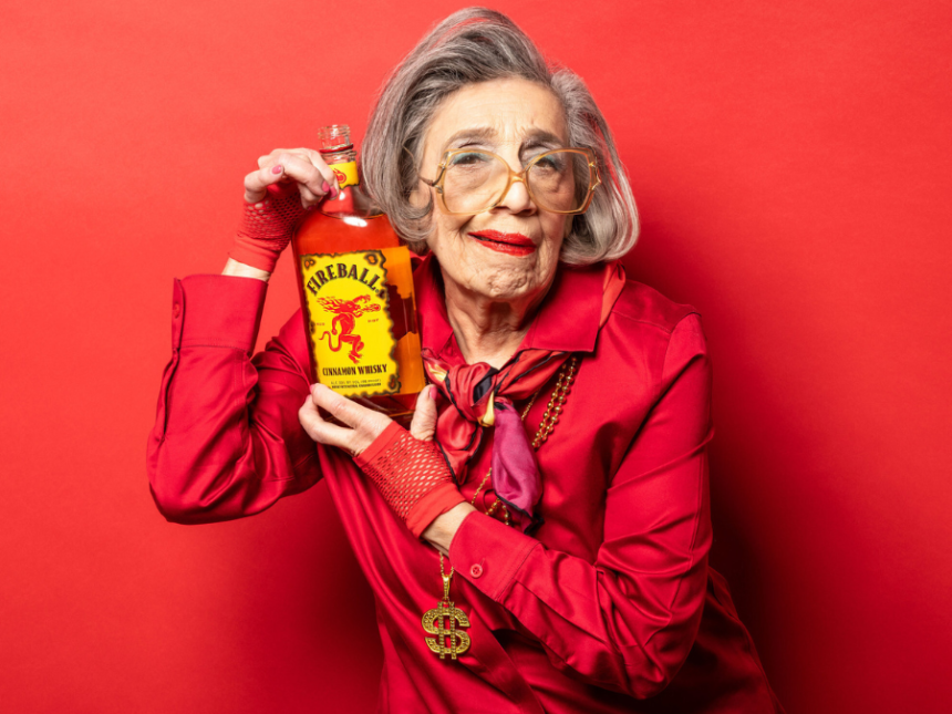 Elderly woman holding bottle of Fireball cinnamon whisky