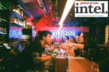 A bartender speaking to drinkers in a crowded bar