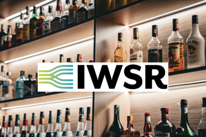 Bottles of alcohol on shelves behind a bar with IWSR logo