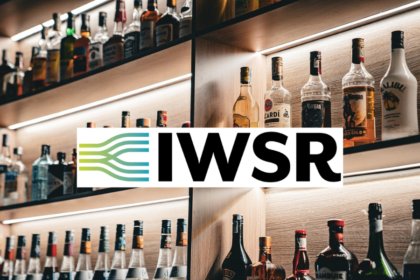 Bottles of alcohol on shelves behind a bar with IWSR logo
