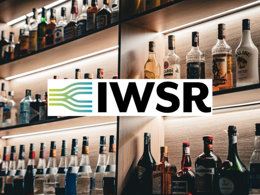 Bottles of alcohol on shelves behind a bar with IWSR logo