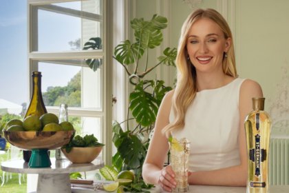 Sophie Turner with St-Germain bottle on a bar