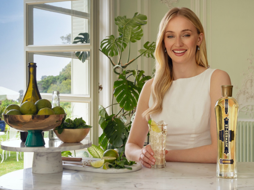 Sophie Turner with St-Germain bottle on a bar