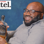 Charles Everett holding a bottle of Fort Mosé 1738 Black-owned American whiskey