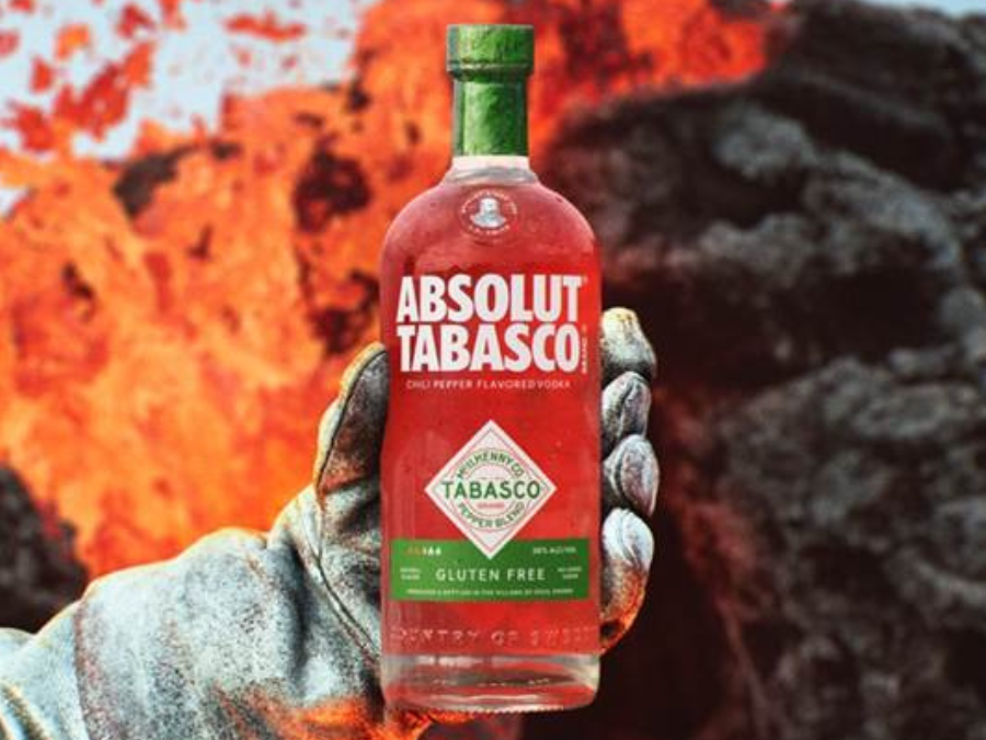 Absolute Tabasco bottle held out by a white gloved hand in front of lava