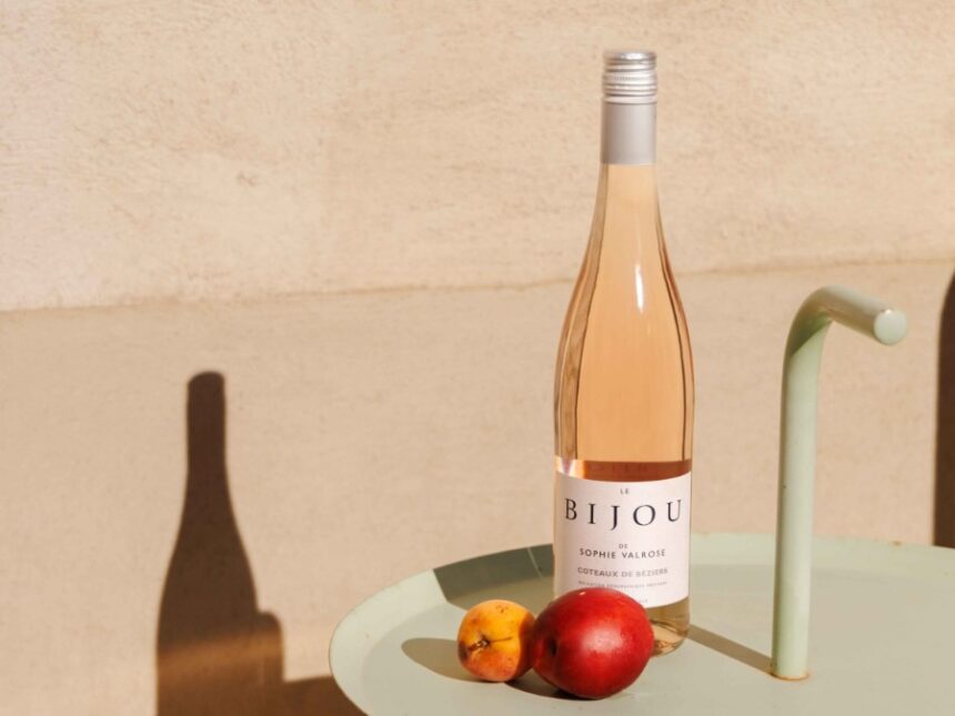 Bottle of rose wine on a sunlit table with an apple