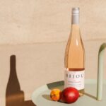 Bottle of rose wine on a sunlit table with an apple