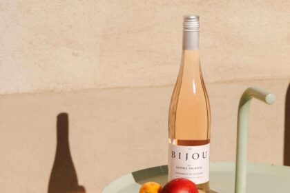 Bottle of rose wine on a sunlit table with an apple