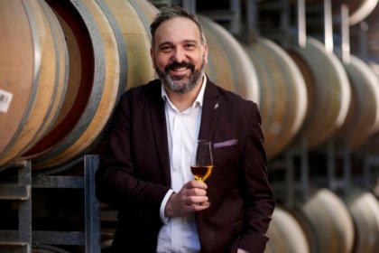 White man smiles holding whisky glass in a barrel room