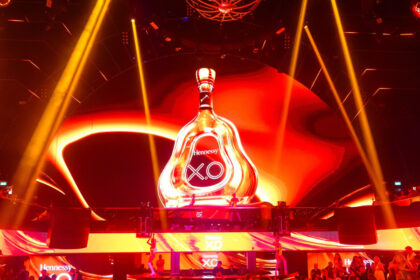 A giant bottle of Hennessey on a stage with red strobe lighting