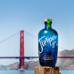 A bottle of Junipero gin in front of the golden gate bridge in San Fran