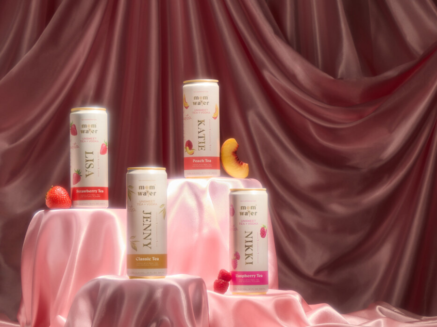 Three cans of vodka beverages on a pink silk sheet