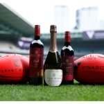 Grant Burge bottles with two Australian footballs