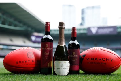Grant Burge bottles with two Australian footballs
