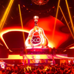 A giant bottle of Hennessey on a stage with red strobe lighting