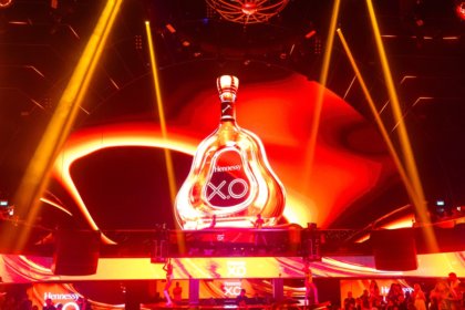 A giant bottle of Hennessey on a stage with red strobe lighting