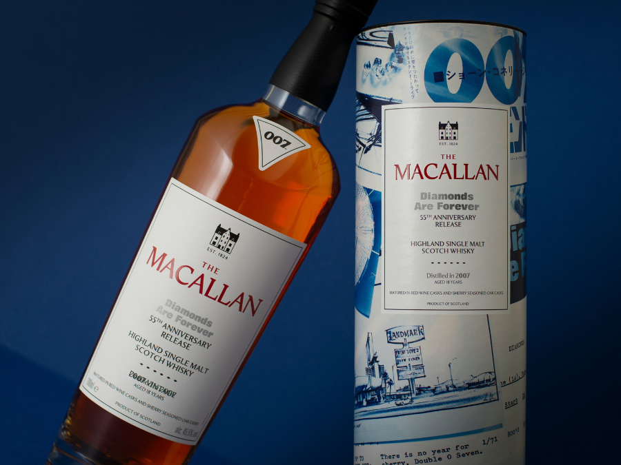 A bottle of whisky leans on a presentation box against blue background