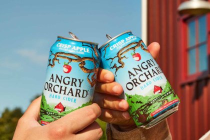 Two hands cheers two cans of angry orchard cider