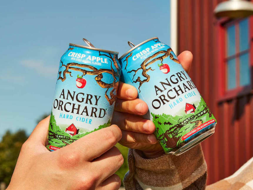 Two hands cheers two cans of angry orchard cider