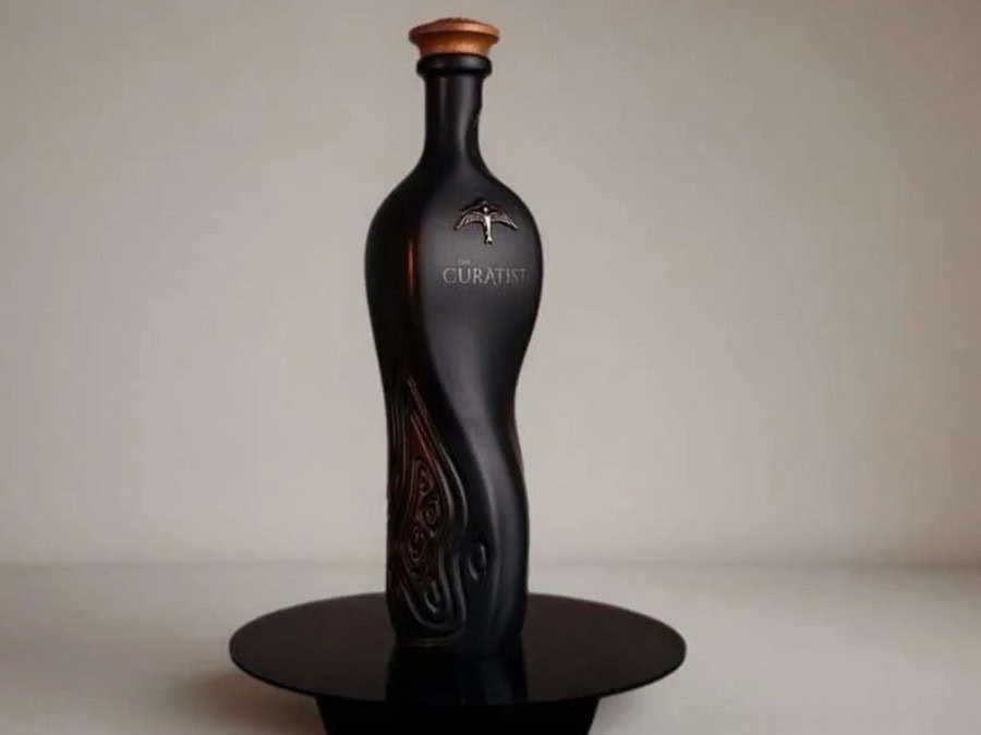 Black curvy bottle of rum on a black plate with grey background