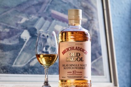 Bottle of whisky next to a glass on a shelf
