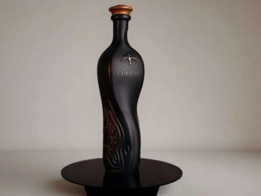 Black curvy bottle of rum on a black plate with grey background