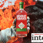 Absolute Tabasco bottle held out by a white gloved hand in front of lava