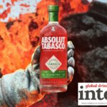 Absolute Tabasco bottle held out by a white gloved hand in front of lava