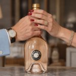 Miraval rose bottle with a male and a female's hands around the neck