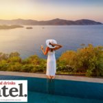 Woman holding a drink looking out at a view of the Mediterranean