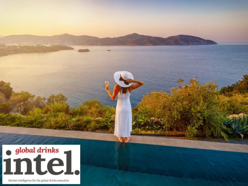 Woman holding a drink looking out at a view of the Mediterranean