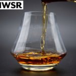Glass of brown spirits with IWSR logo