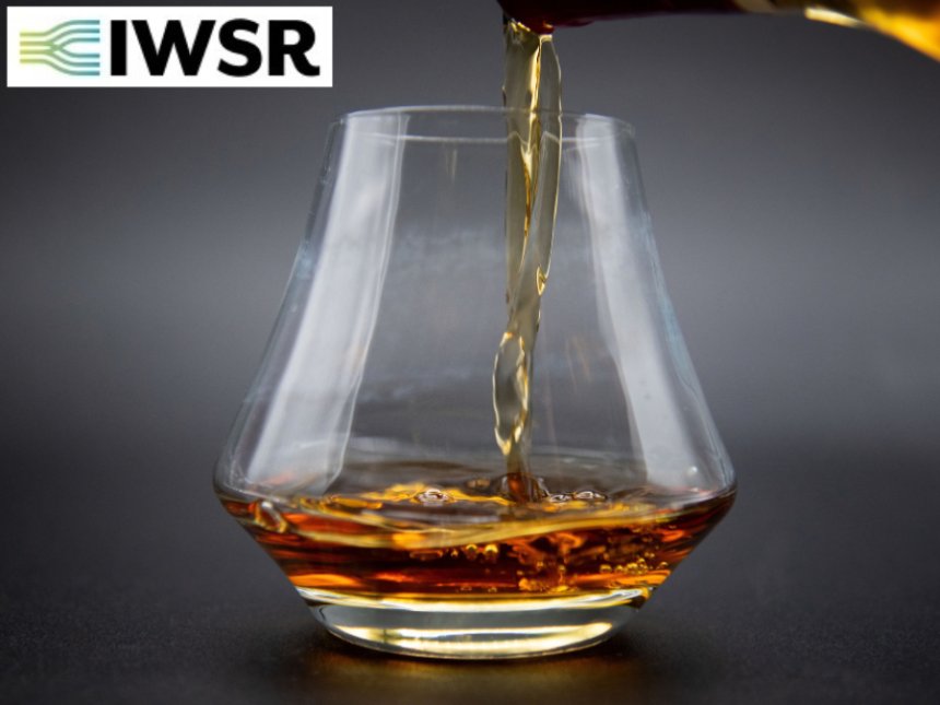Glass of brown spirits with IWSR logo